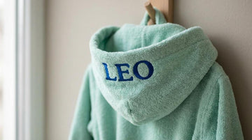 Badekåbe med navn til børn: størrelsesguide, stofvalg og broderiplacering