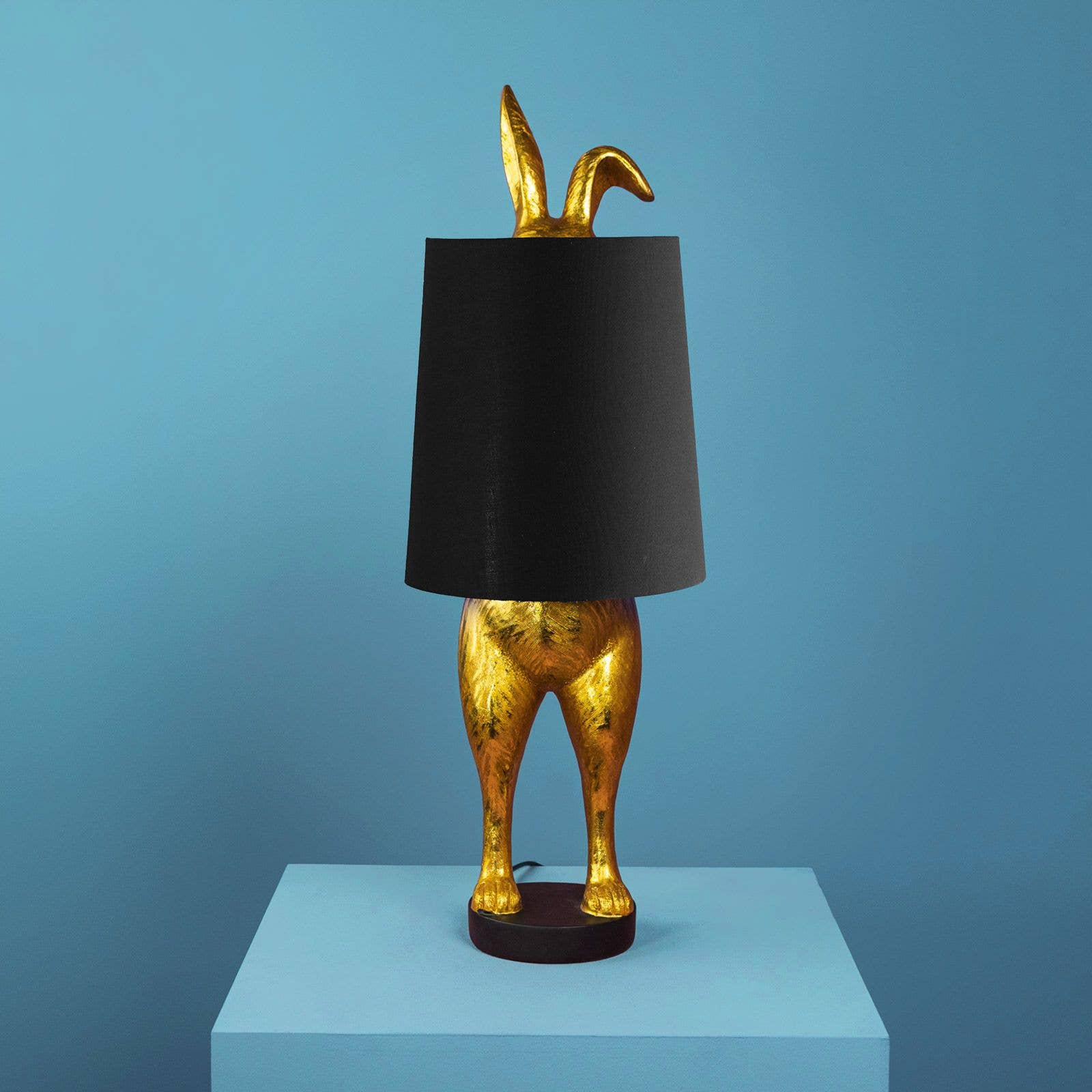 Dekorativ bordlampe Hiding Bunny i guld og sort med form som en kanin.