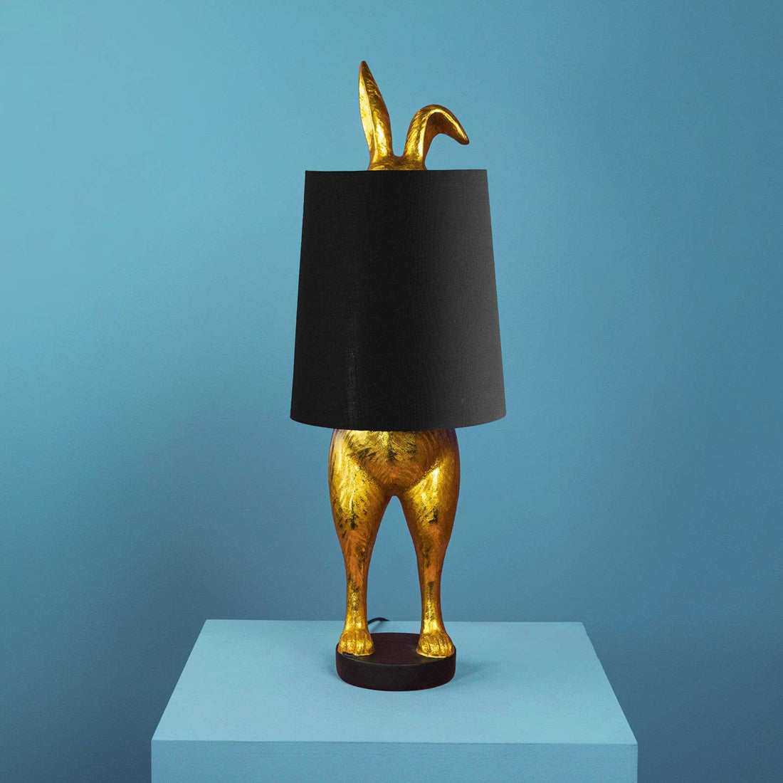 Dekorativ bordlampe Hiding Bunny i guld og sort med form som en kanin.