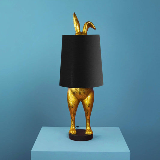 Dekorativ bordlampe Hiding Bunny i guld og sort med form som en kanin.