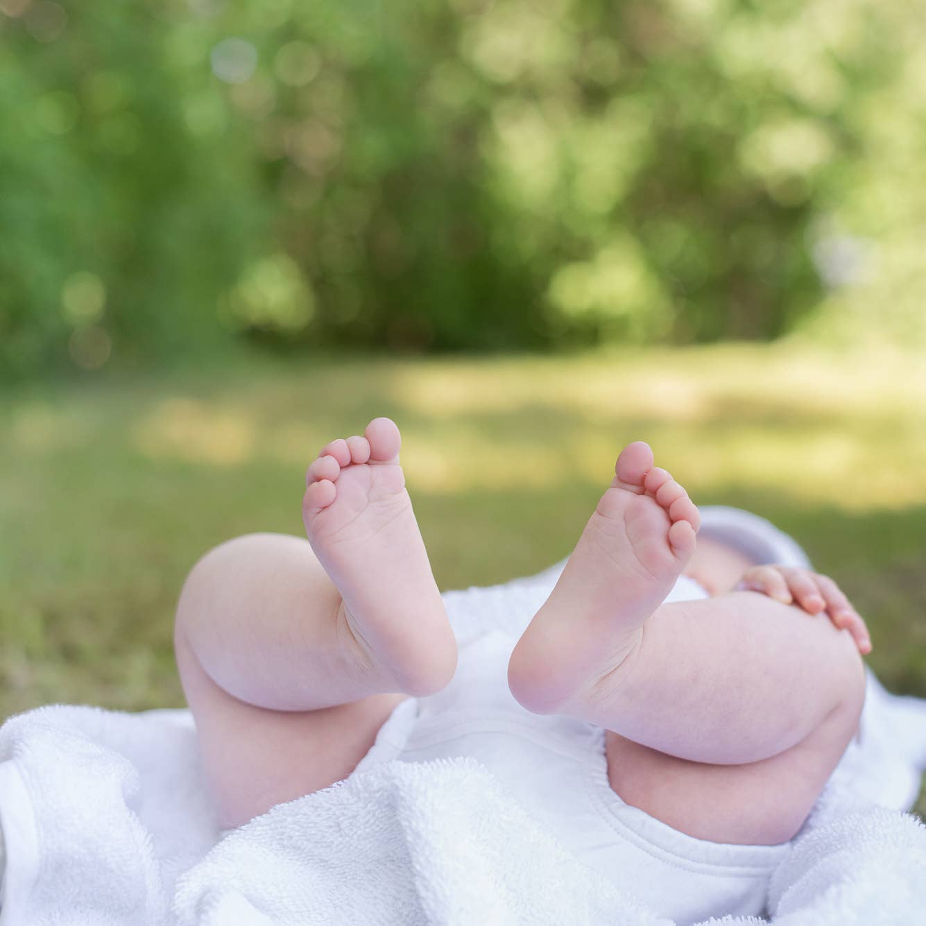 Baby fødder og ben på hvidt økologisk håndklæde med kaninører