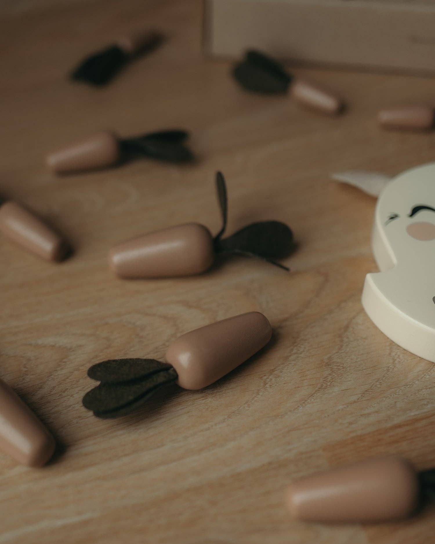 Nærbillede af små trægulerødder fra Bunny Balance Montessori trælegetøj spredt på et træbord.