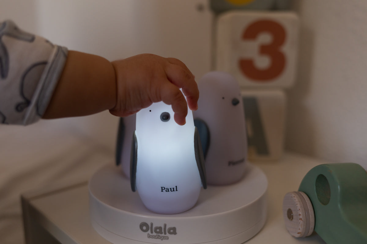 Barnestud hånd på lysende pingvin natlampe med navn på hvid platform