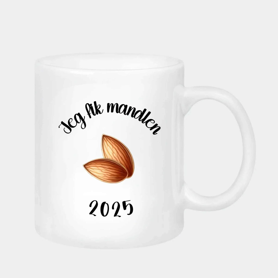 Hvidt keramisk krus 330 ml med tekst "Jeg fik mandlen 2025" og mandelillustration, perfekt som mandelgave