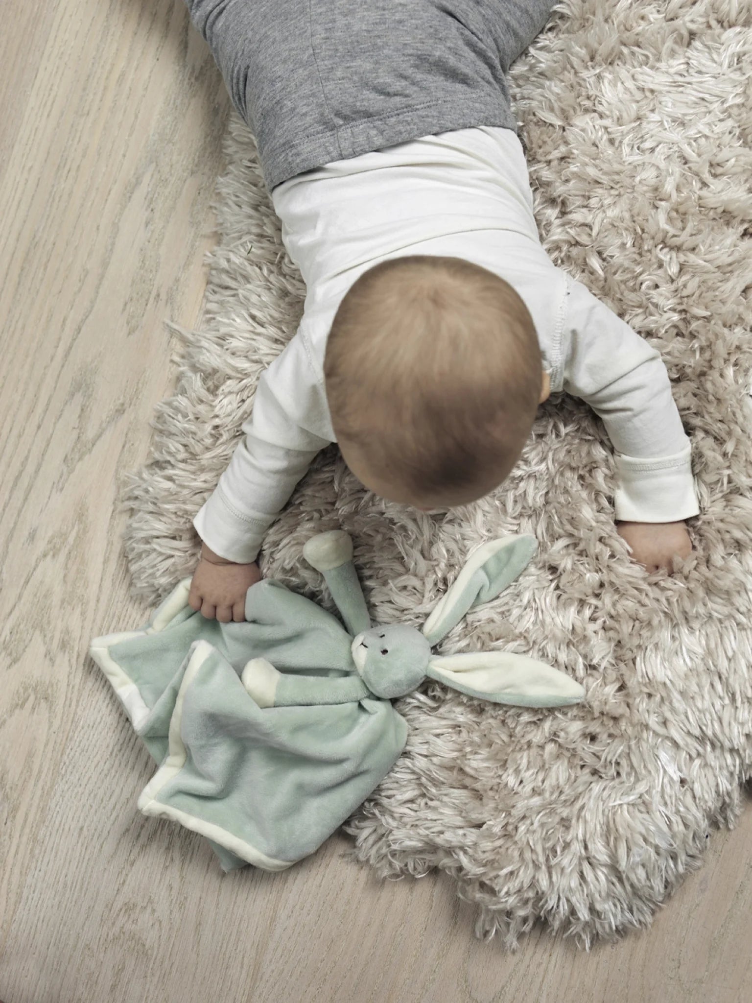 Baby med en grøn Diinglisar-kaninnusseklud på et lyst tæppe