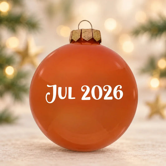 Blank orange julekugle med Jul 2026 på diffus julebaggrund med gran og stjerner