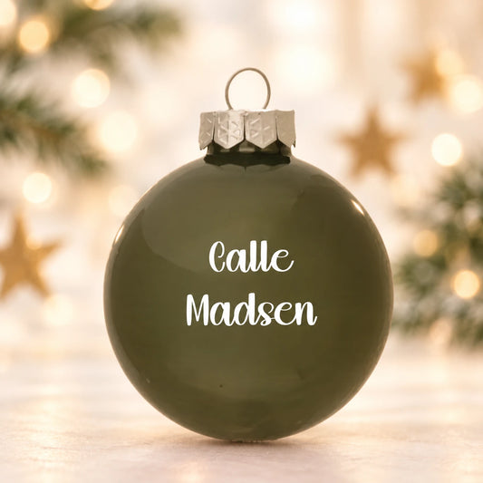 Mat olivengrøn julekugle 57 mm med navnet Calle Madsen på diffus julebaggrund med gran og stjerner