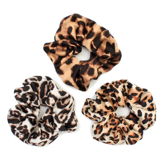 Tre scrunchies med leopardmønster i forskellige nuancer på hvid baggrund