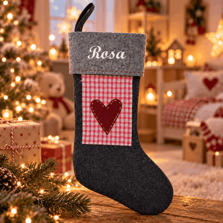 Grå julesok med navnet Rosa broderet, rødternet mønster og et hjerte i hyggelige omgivelser.