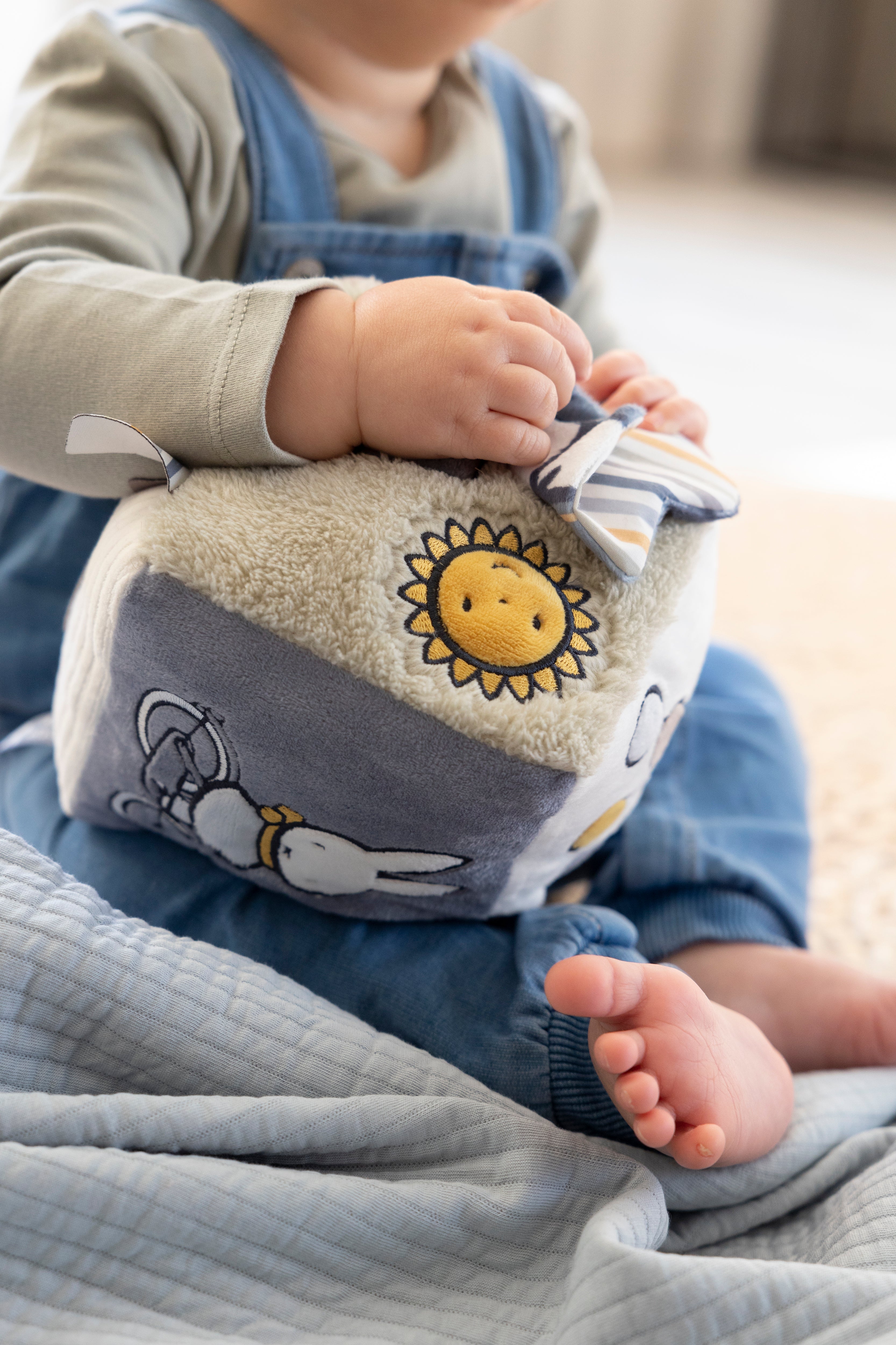Babys hænder der leger med Miffy aktivitetsterning i grøn og hvid.