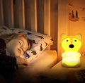 Barn sover trygt med en oplyst LumiPets ræv natlampe ved sengen.