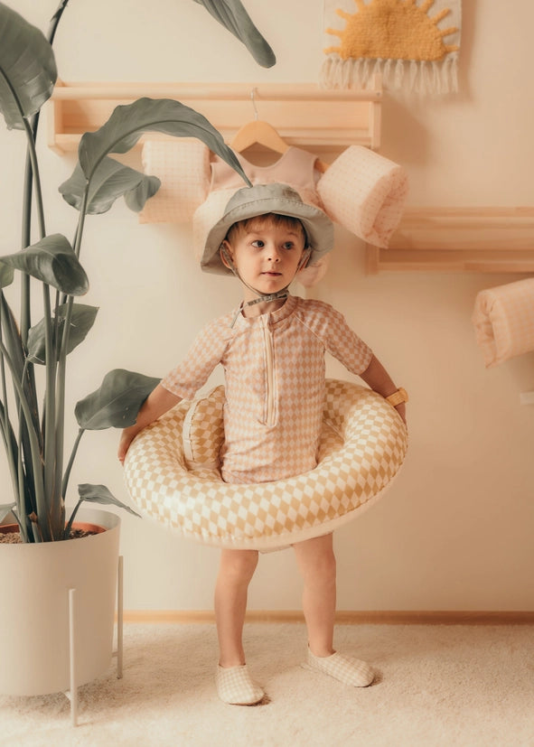 Lille barn i ternet badetøj med den oppustelige babystol i prikket diamant design.