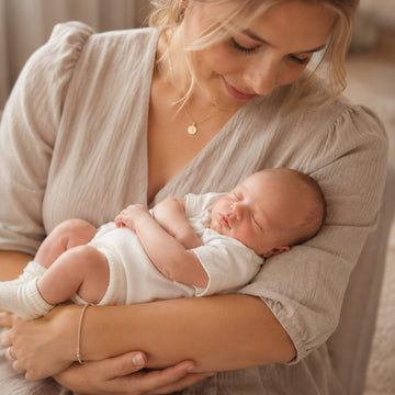 Kvinde der holder sovende baby som symbol på personlige gaver til barnedåb og navngivning.