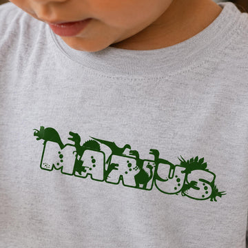 Lysegrå t-shirt til børn med navnet Marius i grøn dino skrift.