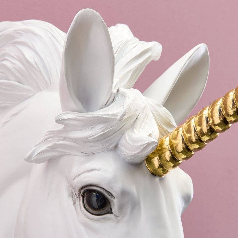 Nærbillede af hvid Hugh enhjørning væglampe med detaljeret gyldent horn og øje.