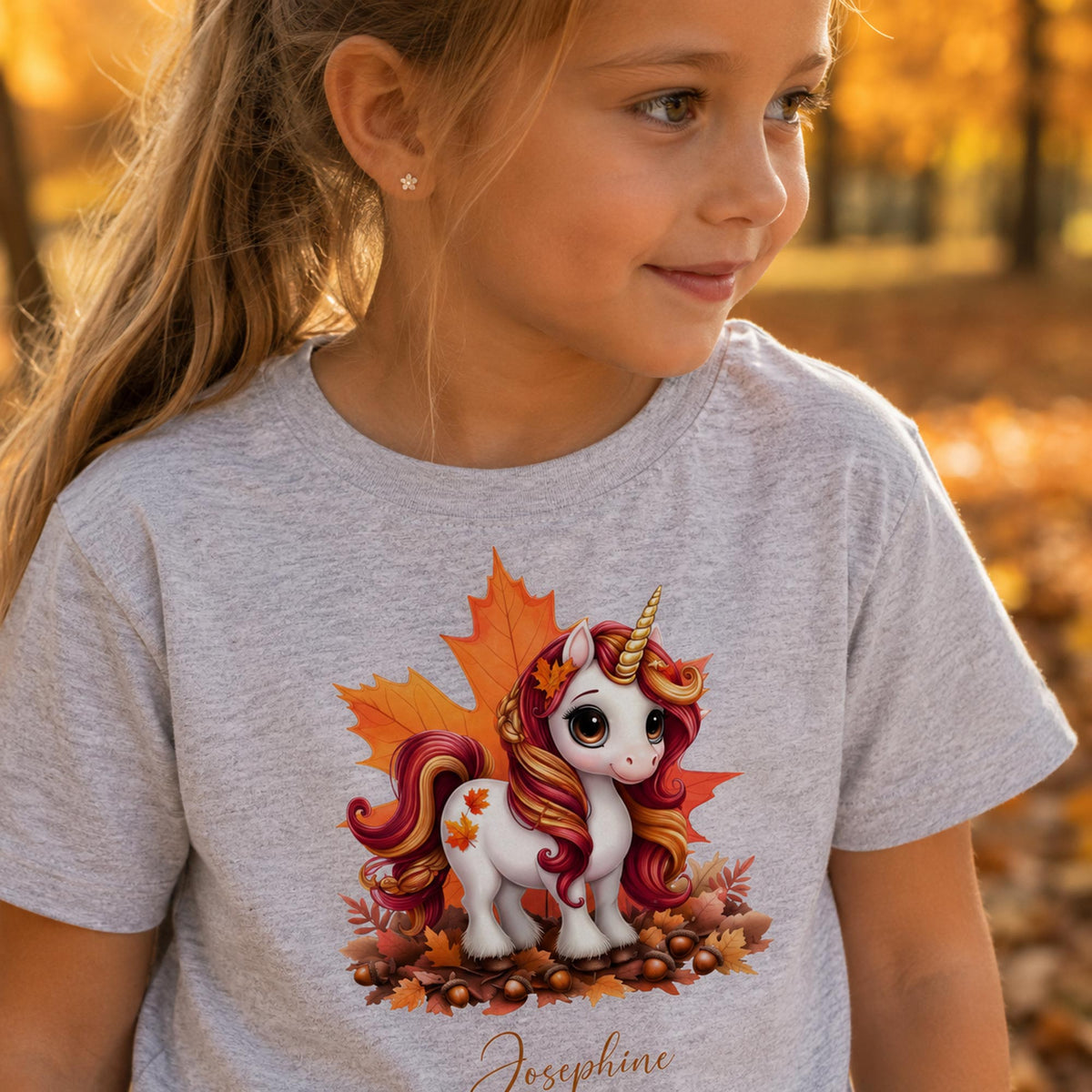 Pige i lysegrå t-shirt med sød efterårs enhjørning og personligt navn Josephine.
