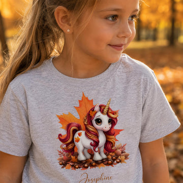 Pige i lysegrå t-shirt med sød efterårs enhjørning og personligt navn Josephine.