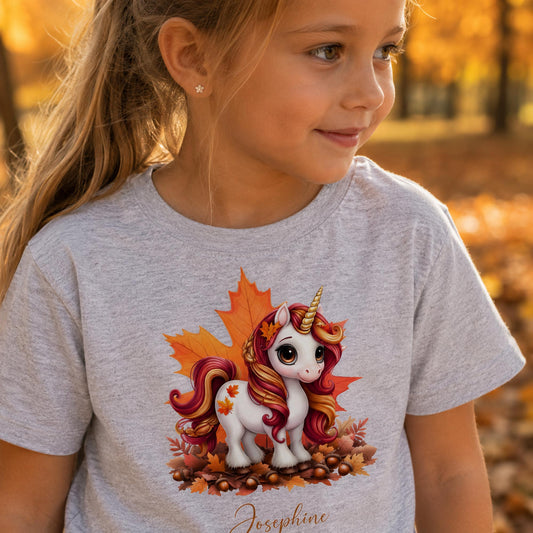 Pige i lysegrå t-shirt med sød efterårs enhjørning og personligt navn Josephine.