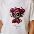Hvid t-shirt til børn med motiv af en uhyggelig dukke og navnet Magnus.
