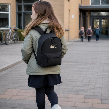 Lille pige med sort rygsæk med navnet Maja broderet på, ideel til skole og institution.