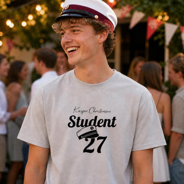Glad ung mand med studenterhue iført personlig grå T-shirt med teksten Student 27.