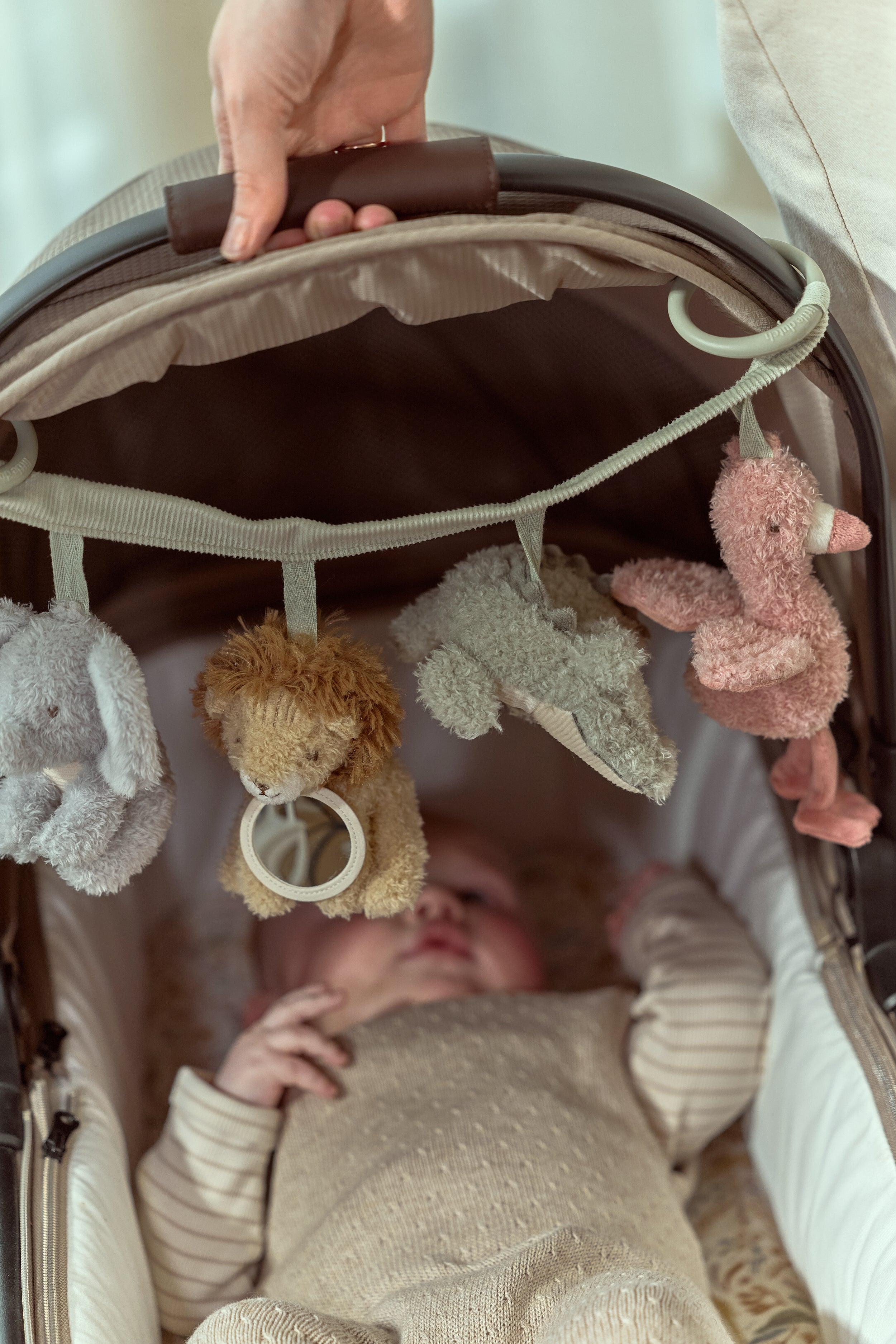 Little Dutch Safari Friends barnevognskæde monteret på en barnevogn med en baby under legetøjet.